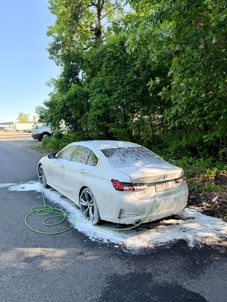 BMW sedan during foam wash — rear view